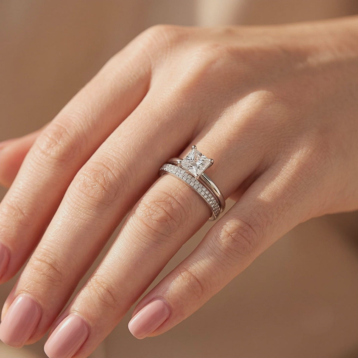 Silver-tone princess-cut solitaire and pavé band stacked together on a finger.