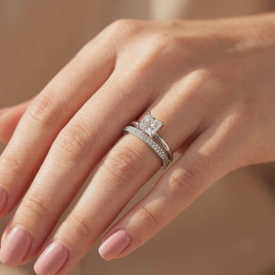 Silver-tone princess-cut solitaire and pavé band stacked together on a finger.