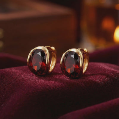 Solid gold huggie earrings with simulated garnet.