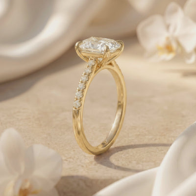 Side view of a gold-tone cushion rectangular solitaire ring with pavé stones along the band