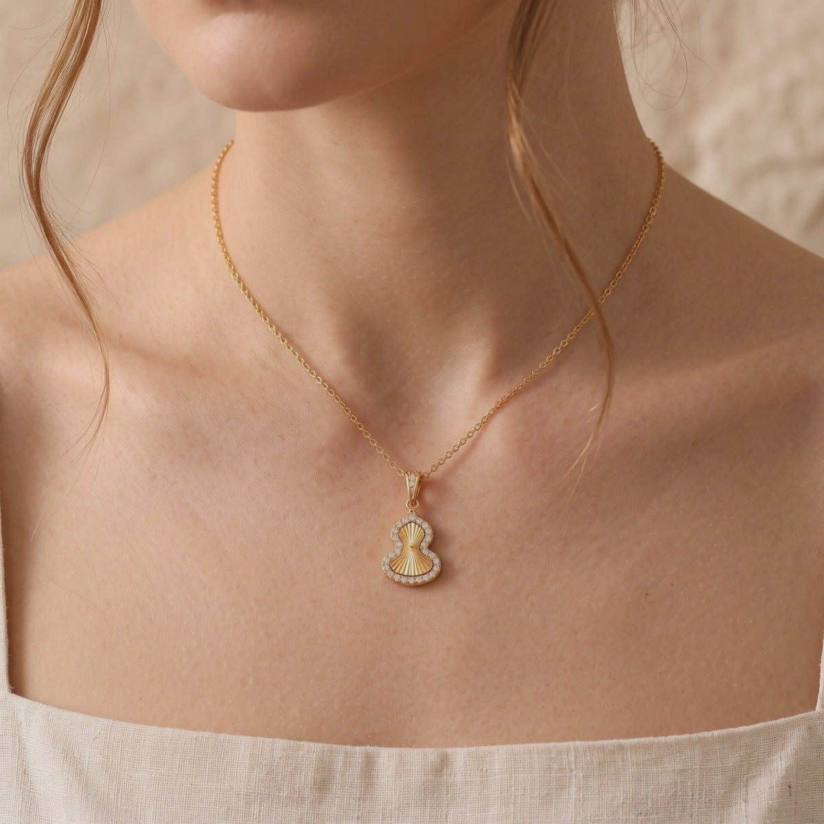 The gold-tone Sorsha necklace with a textured gourd pendant, shown worn on a model's neck.
