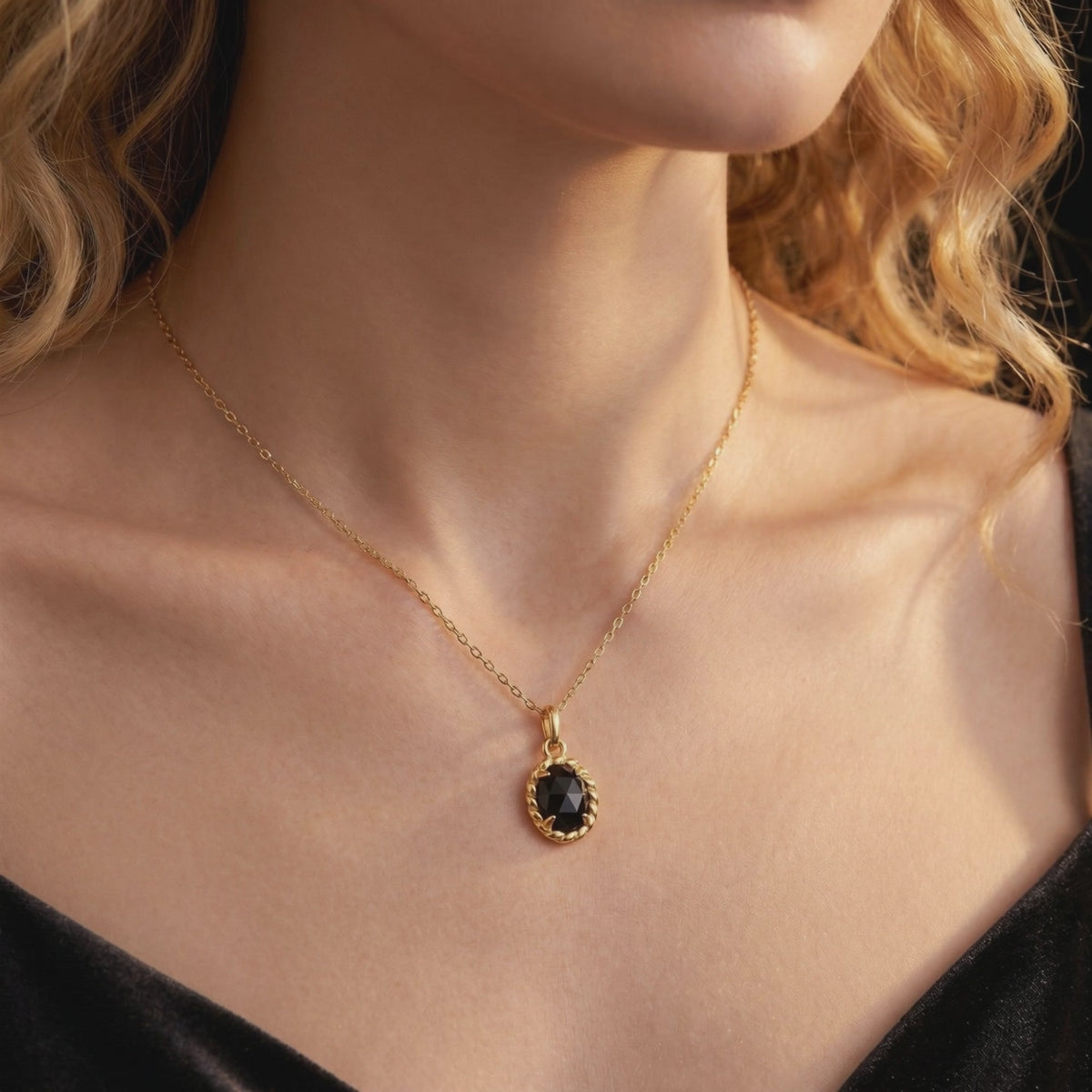 Model wearing a solid gold necklace with an oval black onyx pendant in a twisted border setting.