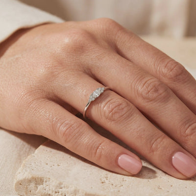 Sterling silver oval moissanite ring with clustered side stones, worn on a hand.