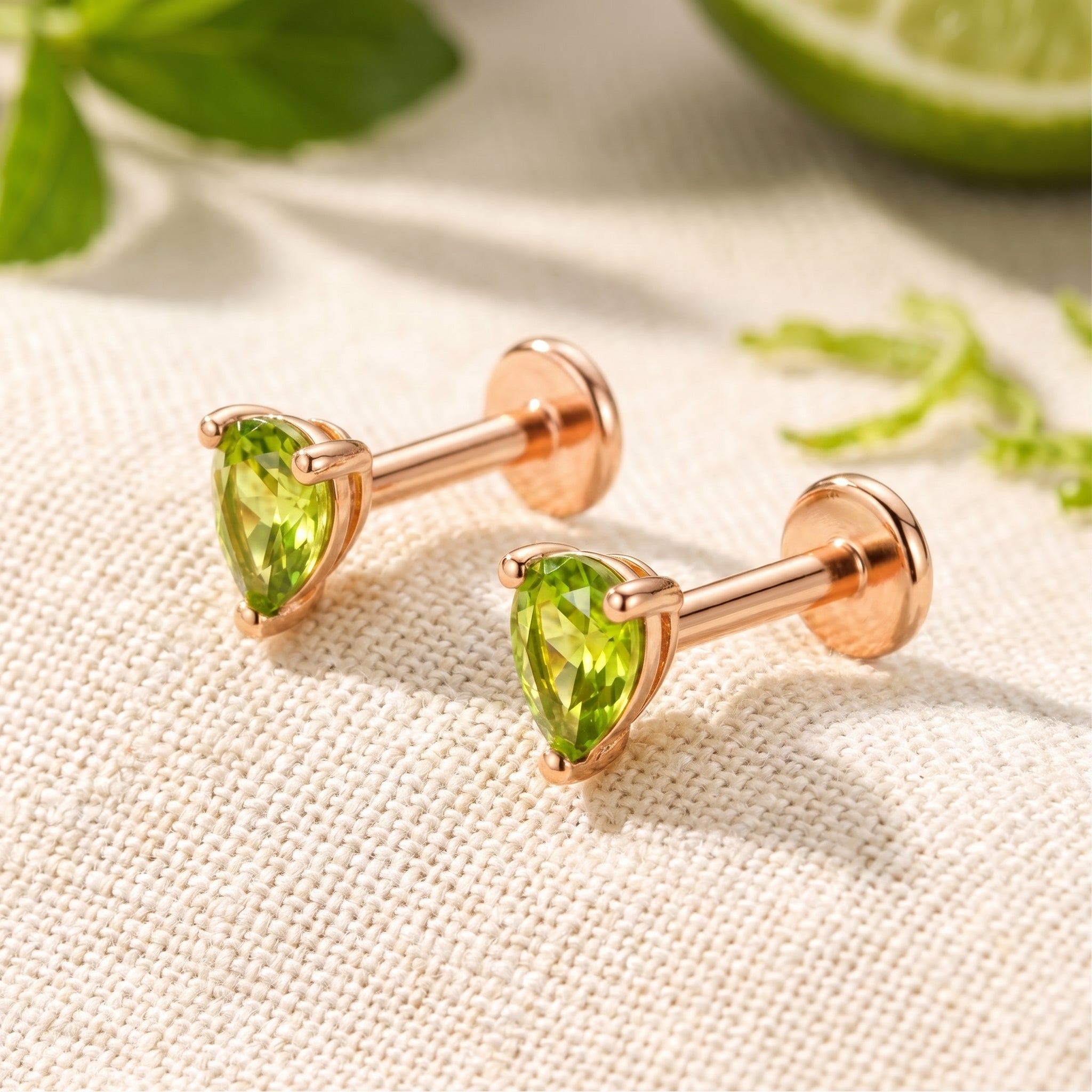 A pair of solid rose gold earrings with simulated peridot.